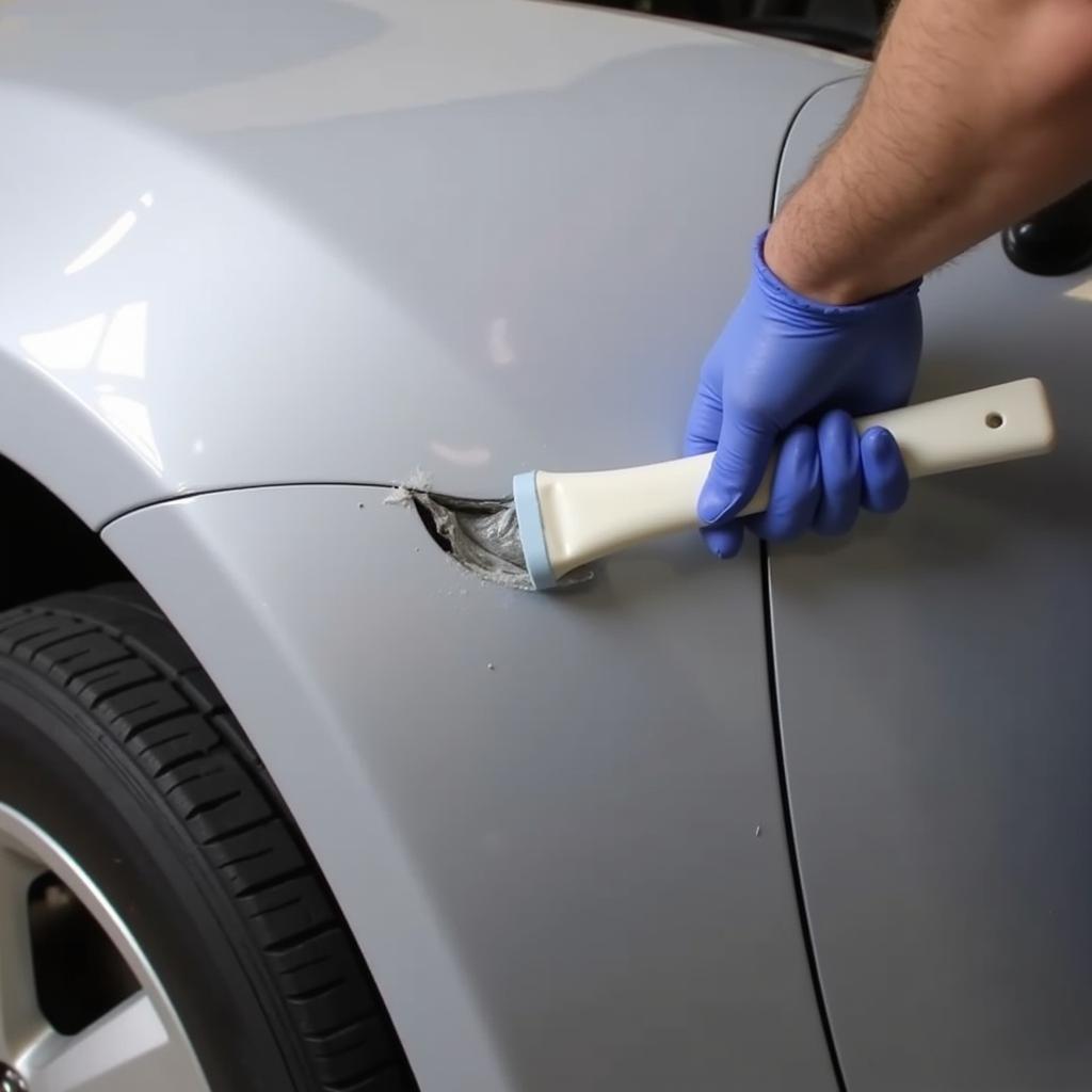 Applying Body Filler to Car Bumper