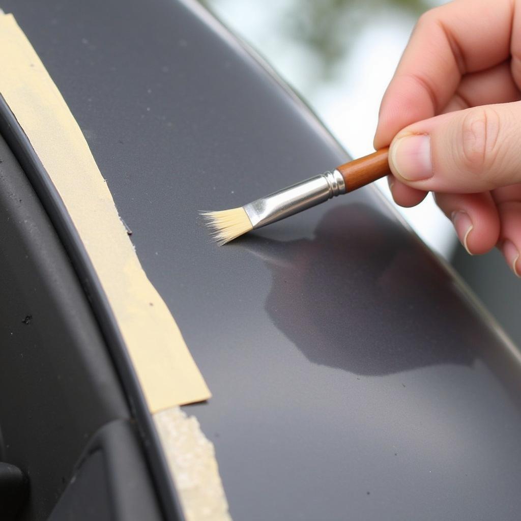 Applying car touch up paint with a fine brush on a small scratch