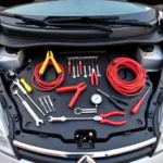 Car Breakdown Tool Kit Essentials: Jumper cables, tire pressure gauge, and various tools laid out on a car hood.