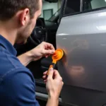 A mechanic using a car door gap tool to adjust a car door, showcasing its practical application.