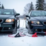 Jumper cables connecting two cars in a snowy landscape