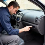 Mechanic locating the OBDII port in a vehicle.