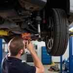 Mechanic Using an Impact Wrench on Car Suspension