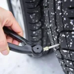 Pliers-style car tire stud remover gripping a tire stud for removal