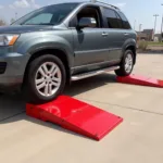 Red car ramps in use, elevating a car for maintenance.