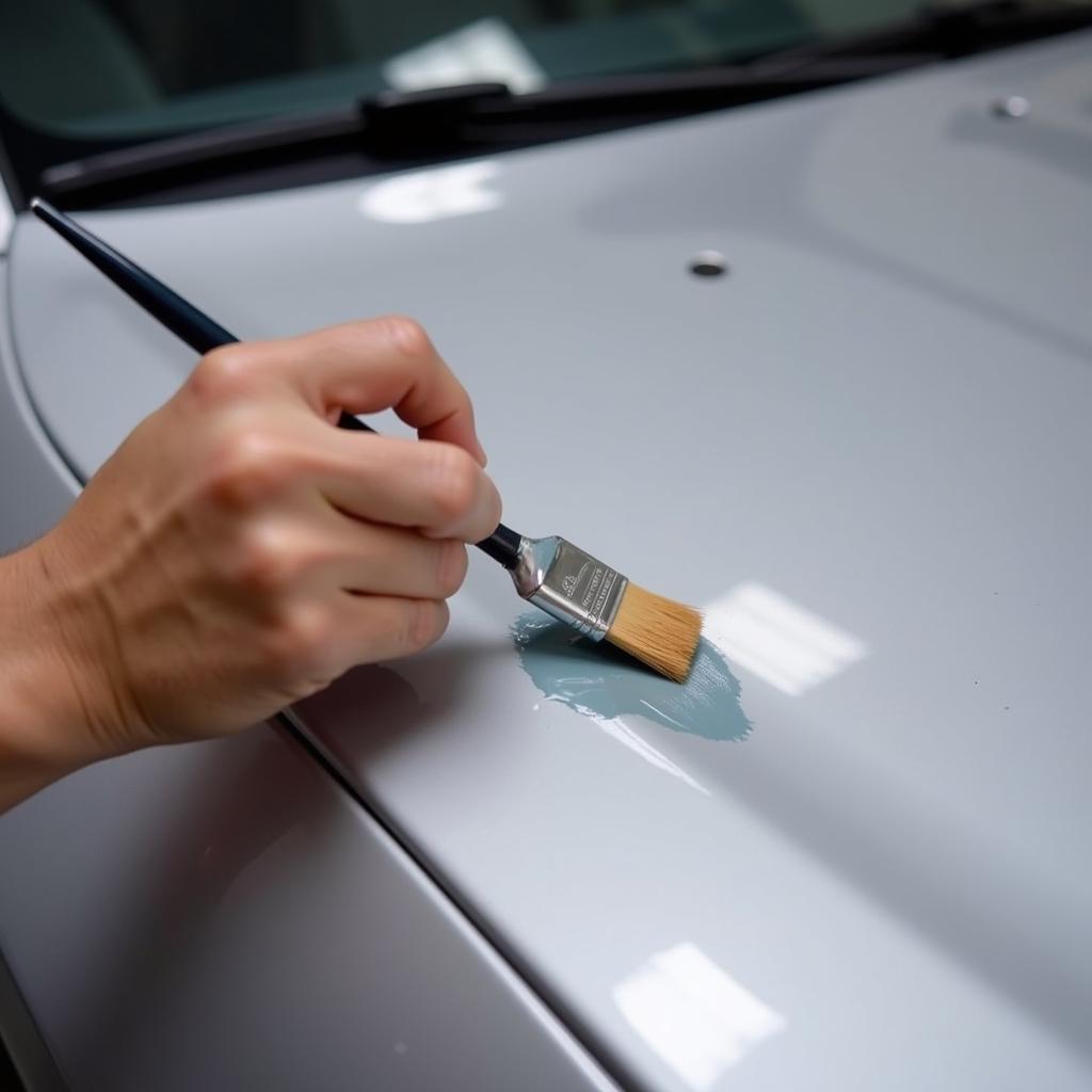 Applying touch-up paint to a car paint chip using a fine-tipped brush.